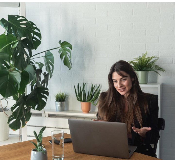 A counsellor hosting a session from a plant-filled desk